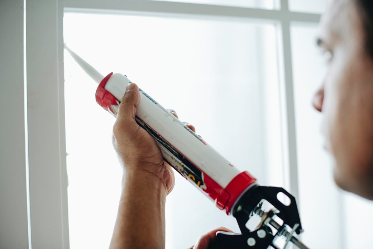 Man Air Sealing Corners of Window in Home