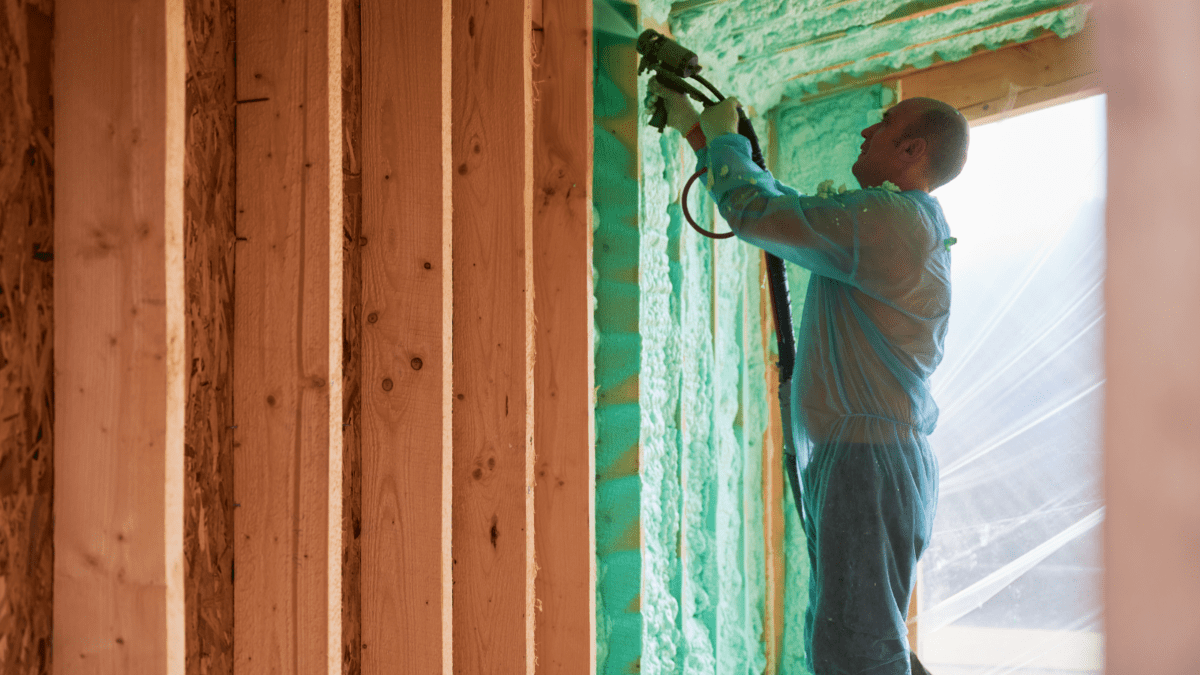 Image of someone applying spray foam insulation to the walls of a room- Foam Insulation Types blog featured image