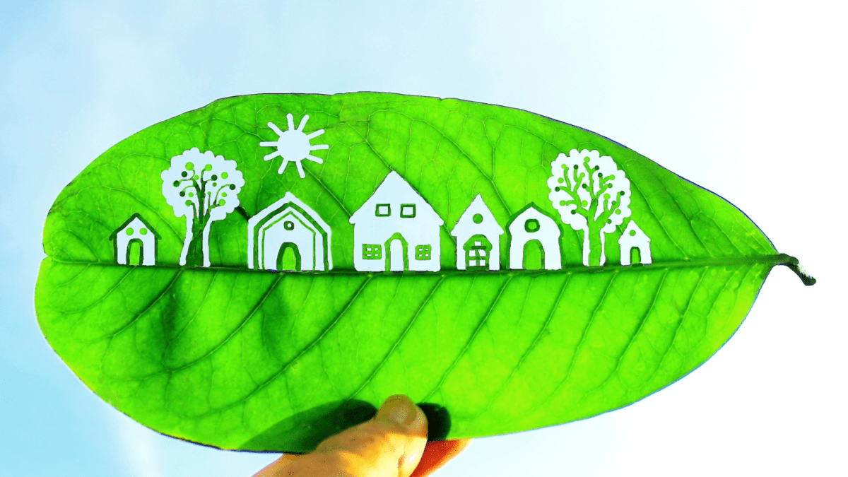 Image of a leaf with cutouts of houses and trees- Sustainable home blog featured image