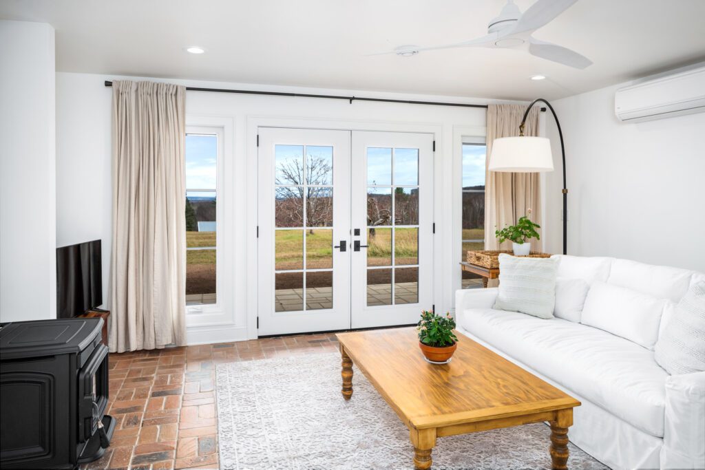 A room with french doors and windows with think beige curtains pulled to the side