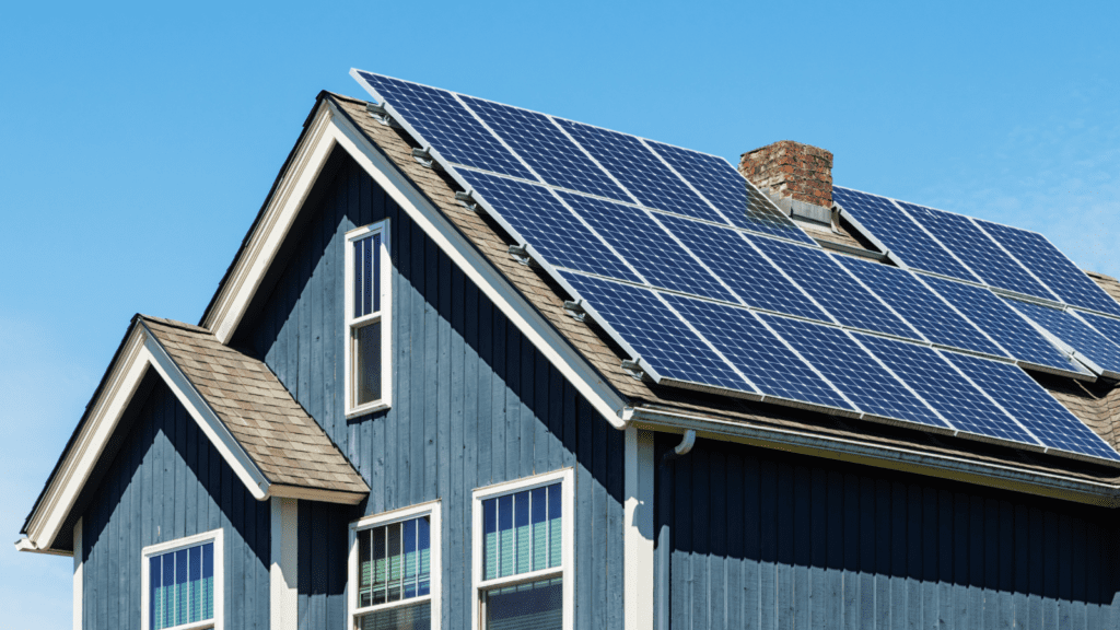 Solar panels on the roof of a blue 2-story house