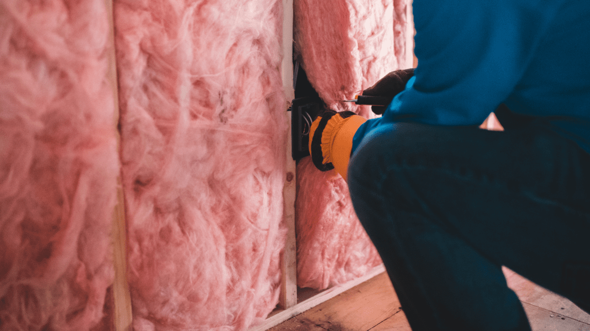 Image of someone installing fiberglass insulation- Thermal Insulation blog featured image